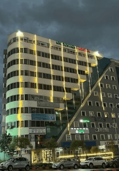 MK Business Center at dusk, its curved façade lit and the roofline sign glowing